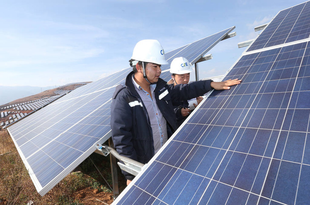 Chinese workers examine solar panels at a photovoltaic power station in Eryuan county, Dali Bai Autonomous Prefecture, southwest China's Yunnan province, 10 December 2015 - Zdjęcie, obraz
