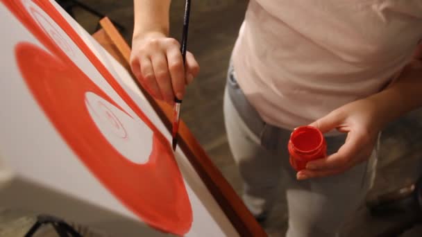 Close-up van de hand van de kunstenaar schilderen een rood hart op een doek op de ezel - Video