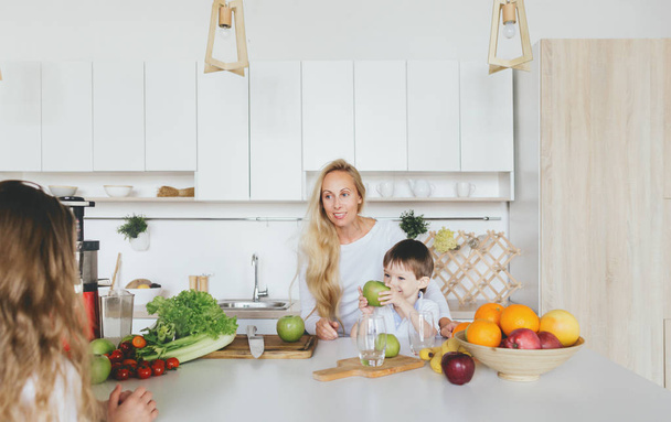 Happy mom with her children cooking breakfast home in kitchen - 写真・画像
