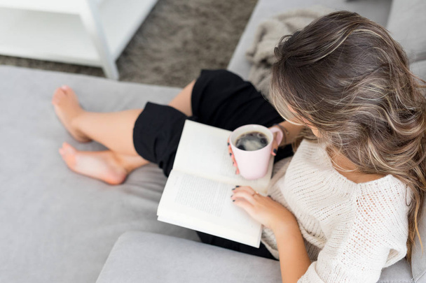 Hermosa joven mujer relajándose en casa leyendo un libro
 - Foto, Imagen