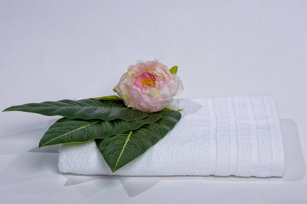 Flower on a white towel. The texture of the fabric. White towel on a white background. Rose bud. Terry towel with a flower on a white background. - Photo, image