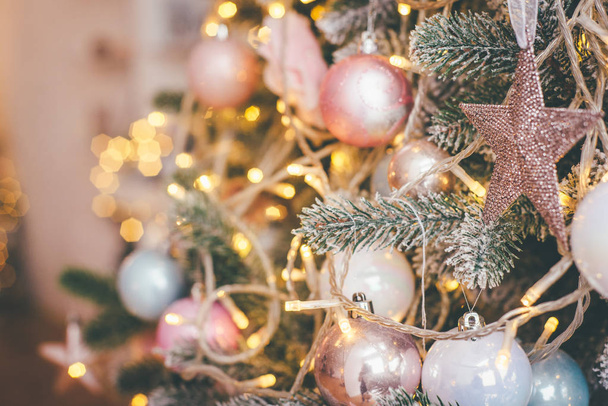 Pastellfarbener Christbaumschmuck und gelbe Weihnachtslichter in der Nahaufnahme - Foto, Bild