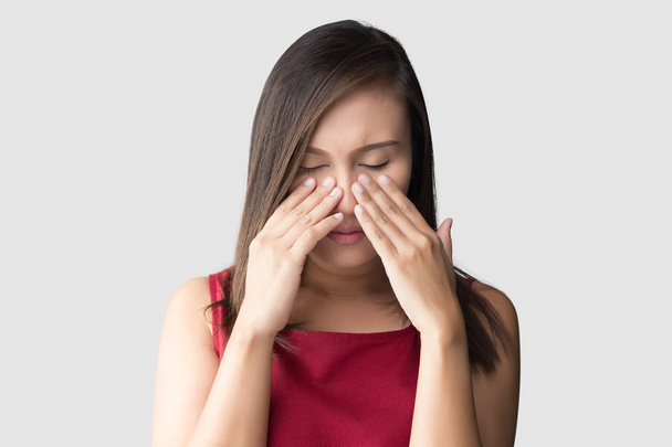 Aziatische vrouw in rode slijtage onwel wegens sinus tegen een grijze achtergrond. Mensen gevangen een koude en koorts. Het concept van de gezondheidszorg en allergie - Foto, afbeelding