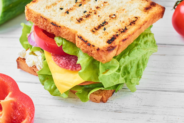 sendvič se šunkou, hlávkovým salátem a čerstvou zeleninou na bílém pozadí zblízka - Fotografie, Obrázek