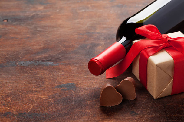 Valentinky den blahopřání s láhví vína, čokoládové srdce a Dárkový box na dřevěné pozadí. S prostorem pro vaše pozdravy - Fotografie, Obrázek