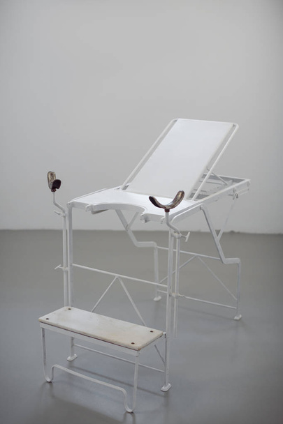 Old style chair for women diagnosis agaist white wall. Gynie exam table in museum. - Фото, зображення