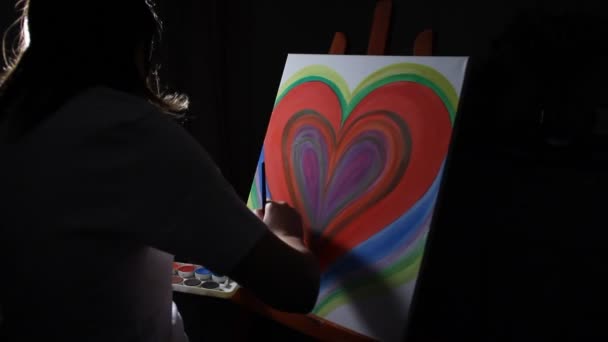 крупным планом женщина-художник рисует большое красное сердце на мольберте в своей студии на темном черном фоне
 - Кадры, видео