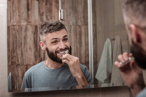 Handsome bearded man brushing his teeth in the morning - Foto, Imagen