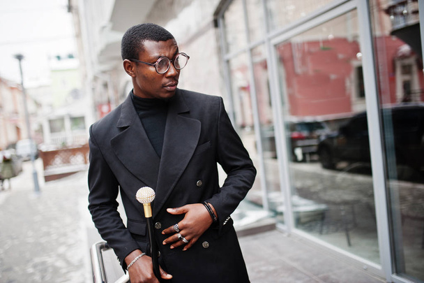 Stylish african american gentleman in elegant black jacket, holding retro walking stick as cane flask or tippling cane with golden diamond ball handle. Rich fashionable afro man. - Foto, Imagem
