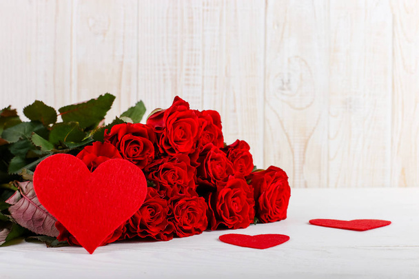 Red roses and hearts on white wooden table. Concept Women's Day or St. Valentine. Copy space. - 写真・画像