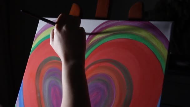 女性アーティストの絵画暗い黒背景に彼女のスタジオのイーゼルに大きな赤いハートのクローズ アップ - 映像、動画