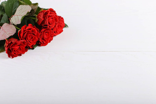 Red roses bouquet on white wooden table. Concept Women's Day or St. Valentine. Copy space. - Zdjęcie, obraz