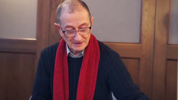 A senior man watch photos and speaks at camera - Video, Çekim