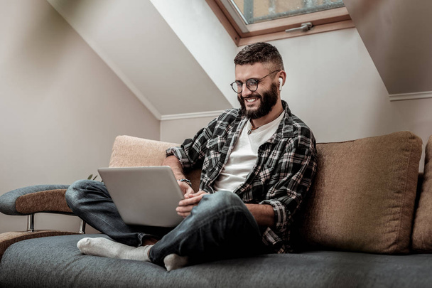 Cheerful happy man sitting on the sofa with his laptop - Photo, image