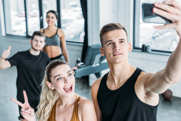 groupe multiethnique de jeunes amis sportifs prenant selfie avec smartphone dans la salle de gym
 - Photo, image