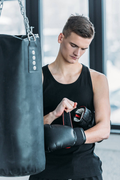 serious young sportsman wearing boxing glove in gym - Foto, Imagem
