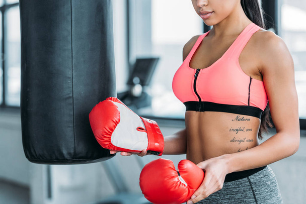 cropped shot of sporty african american girl holding boxing gloves in gym - Φωτογραφία, εικόνα