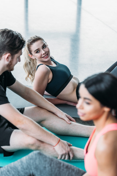 Selektiver Fokus eines jungen Mannes im Gespräch mit sportlichen Mädchen im Fitnessstudio - Foto, Bild