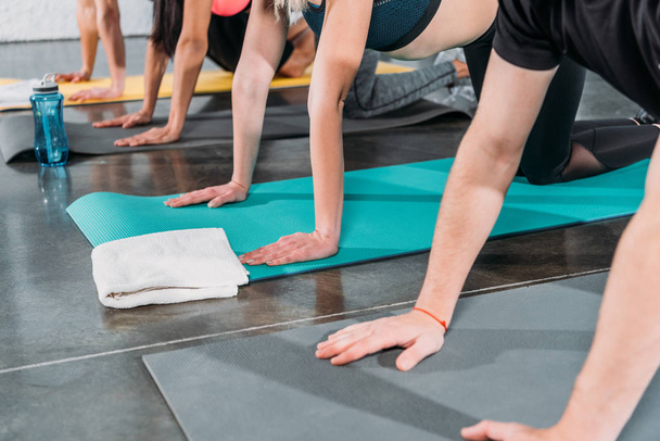 tiro recortado de jóvenes haciendo ejercicio sobre colchonetas de yoga en el gimnasio
 - Foto, Imagen