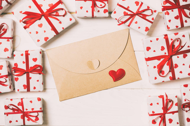 Briefumschlag mit rotem Herz und Geschenkschachtel über hölzernem Vintage-Hintergrund. Valentinstag Karte, Liebe oder Hochzeitsgruß Konzeption. - Foto, Bild