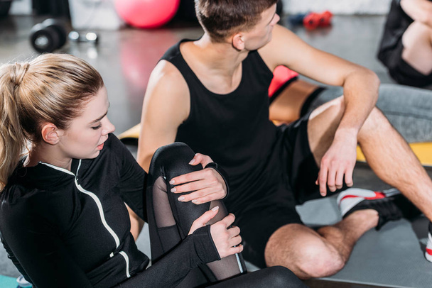 sporty young woman suffering from knee pain after injury in gym - Φωτογραφία, εικόνα