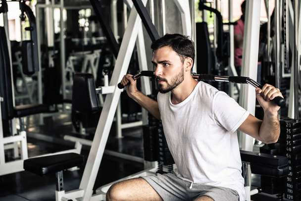 Handsome man is rowing exercise with bodybuilder machine in fitness club.,Portrait of strong man doing working out calories burning in gym., Healthy and fitness sport gym concept. - Photo, Image