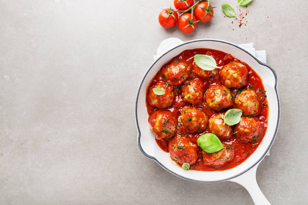 Zelfgemaakte gehaktballen met tomatensaus en kruiden geserveerd in de pan op een grijze achtergrond - Foto, afbeelding