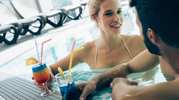 Happy attractive couple relaxing in spa swimming pool - Photo, image