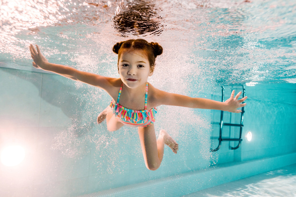 adorable niño nadando bajo el agua en agua azul en la piscina
  - Foto, Imagen