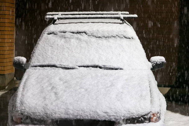 Car covered with snow at night during heavy snow - Photo, Image