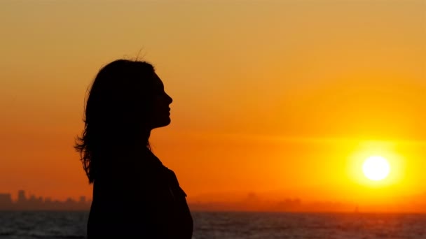 Profiel silhouet van een vrouw inademen van frisse lucht bij zonsondergang op het strand - Video