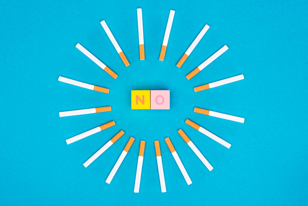 Couché plat avec des cubes de lettres colorées et des cigarettes isolées sur bleu, arrêter de fumer concept
 - Photo, image