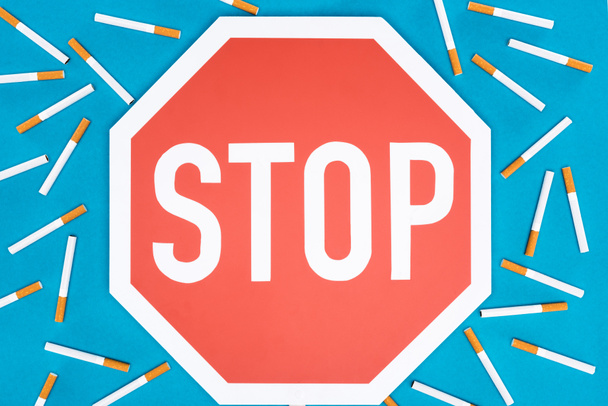 Studio plan de grand panneau stop avec des cigarettes isolées sur bleu, arrêter de fumer concept
 - Photo, image
