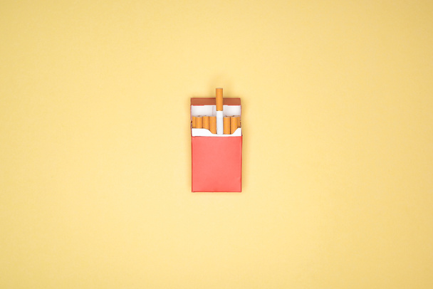 Studio shot of red pack of cigarettes isolated on yellow  - Photo, Image