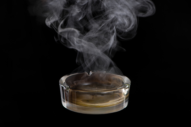 Studio shot of glass ashtray on black - Foto, afbeelding