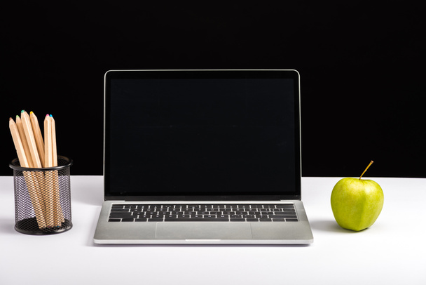 μήλο, φορητό υπολογιστή με την κενή οθόνη και μολύβια που απομονώνονται σε μαύρο - Φωτογραφία, εικόνα