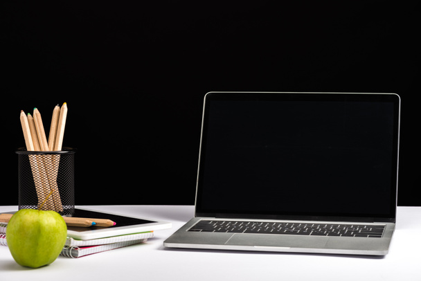 maçã, cadernos, lápis e laptop com tela em branco isolado em preto
 - Foto, Imagem