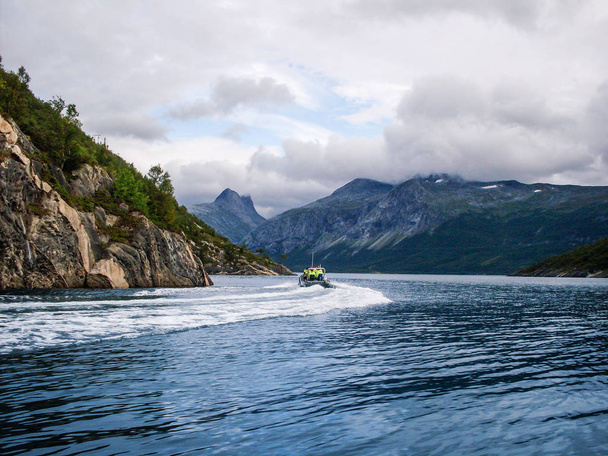 Barco deixa trilha no mar contra o pano de fundo das montanhas norueguesas. Viagem de aventura aquática na paisagem da natureza
 - Foto, Imagem