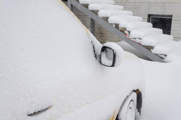 Carro congelado compacto amarelo van coberto de neve no dia de inverno. Cena urbana da vida da cidade no inverno na tempestade de neve
 - Foto, Imagem