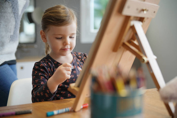 junges Mädchen zeichnet selbst auf Staffelei zu Hause - Foto, Bild