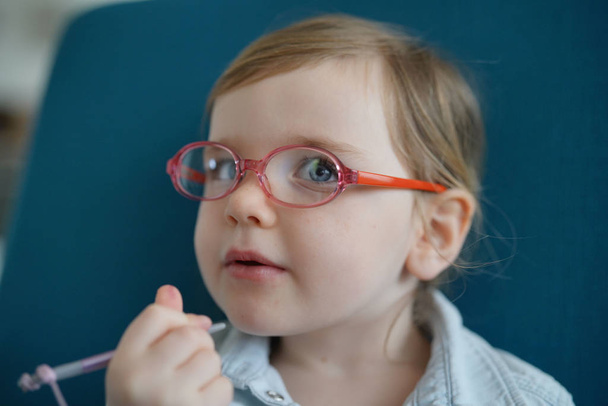 Portrait of young blue eyed girl wearing glasses playing with tablet - Foto, Imagen