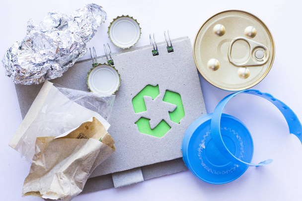 Concepto de protección ambiental, ecología y reciclaje, letrero de reciclaje, bloc de notas y basura sobre fondo blanco vista superior
 - Foto, Imagen