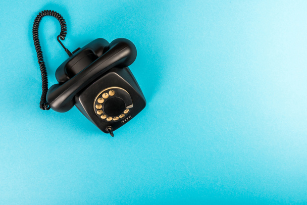top view of black rotary dial telephone isolated on blue with copy space  - Фото, изображение