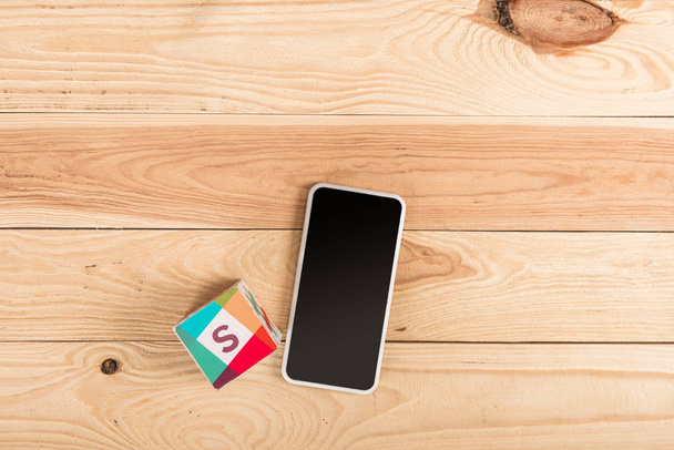 top view of slack icon and smartphone with blank screen on wooden table - Foto, Bild