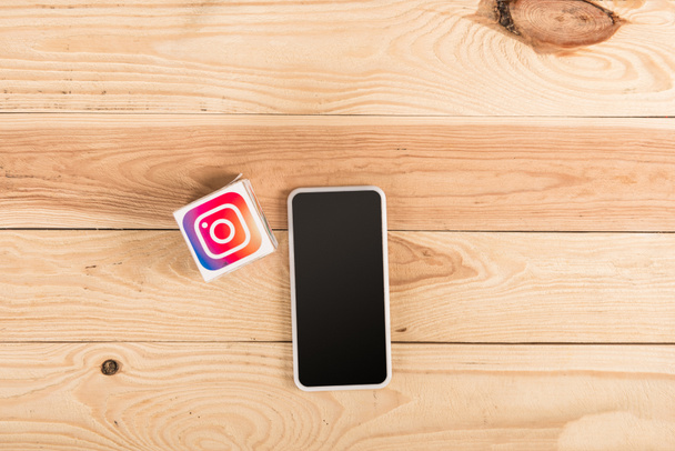 top view of instagram icon and smartphone with blank screen on wooden table - Фото, зображення
