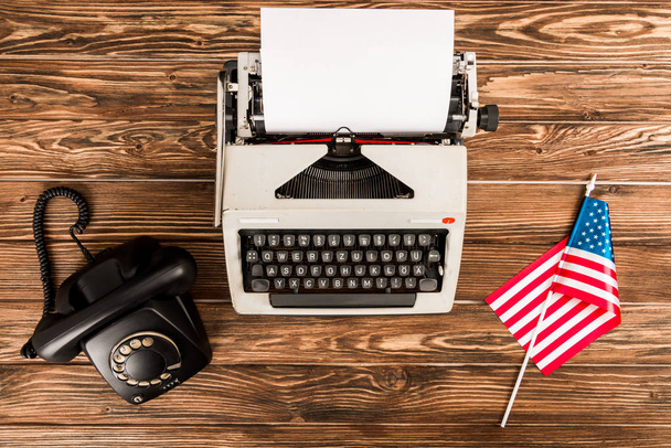 top view of typewriter, rotary dial telephone and american flag on wooden table - Fotoğraf, Görsel