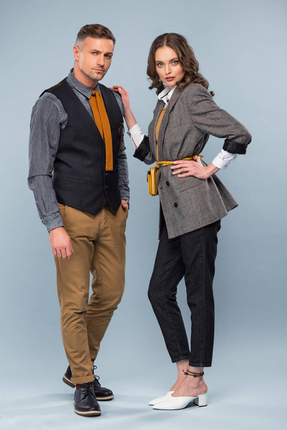 beautiful stylish couple in formal wear looking at camera while posing on grey background - Fotoğraf, Görsel