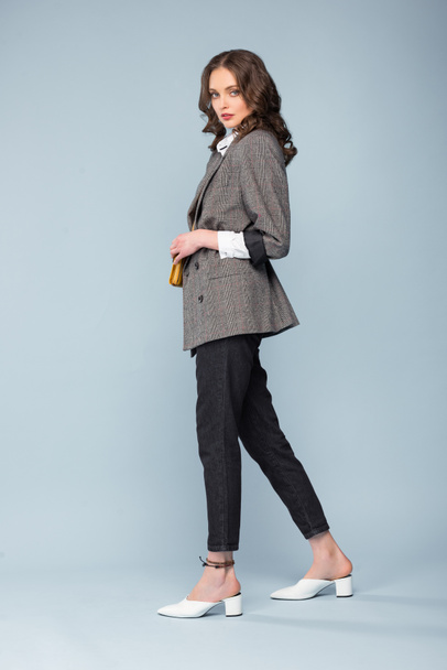 beautiful fashionable woman in formal wear posing and looking at camera on grey background - Φωτογραφία, εικόνα