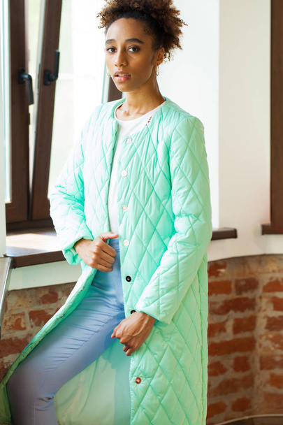 Portrait of an African model woman in a green spring jacket and blue pants - Foto, immagini