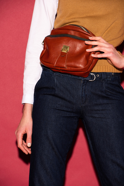 partial view of woman holding leather bag on red background - Photo, Image